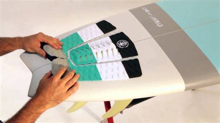 How do you clean a surfboard before putting on a traction pad?